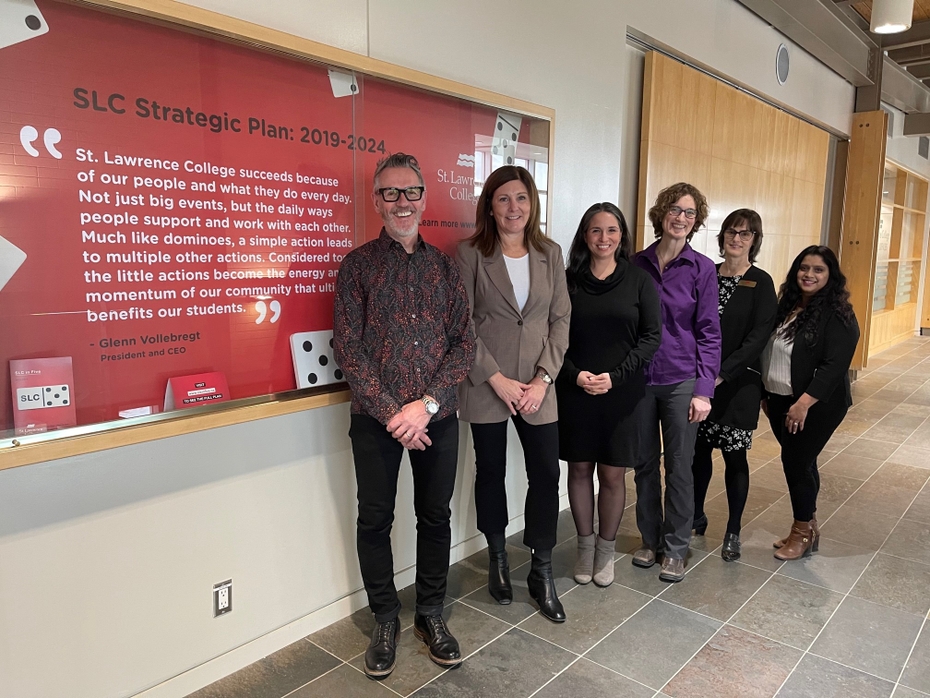 Glenn Vollebregt, SLC President & CEO, Natalie Pierre, Parliamentary Assistant to the Minister of Colleges and Universities, Tania Nicholls, SLC Counsellor, Accessibility, Stacy Gall, Student Counsellor, Shelley Aylesworth-Spink, SLC VP, Student Success, Neetu Shah, the new Associate Director of Student Wellness and Accessibility, stand side by side in a hallway on SLC's Kingston campus